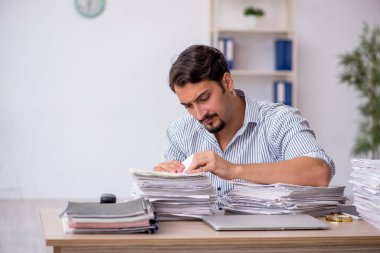 Ofisteki aşırı işten memnun olmayan genç bir erkek işçi.