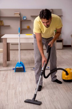 Genç adam evde ev işi yapıyor.