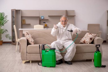 Yaşlı erkek müteahhit evde haşere kontrolü yapıyor.