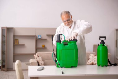 Yaşlı erkek müteahhit evde haşere kontrolü yapıyor.