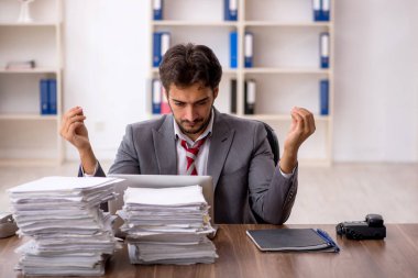 Ofisteki aşırı işten memnun olmayan genç bir erkek işçi.