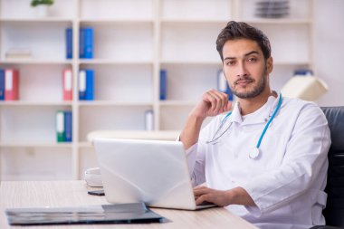 Klinikte çalışan genç erkek doktor.