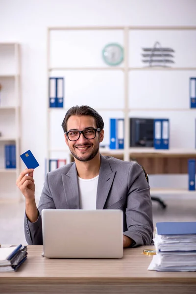 Young male employee holding credit card at workplace — Stock Photo, Image