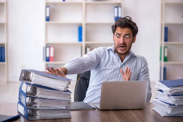 Jovem funcionário masculino infeliz com excesso de trabalho no escritório — Fotografia de Stock