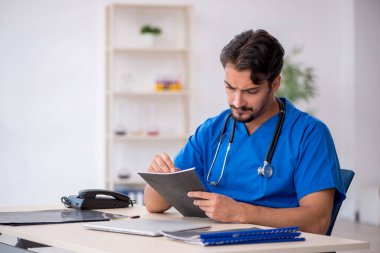 Klinikte çalışan genç erkek doktor.