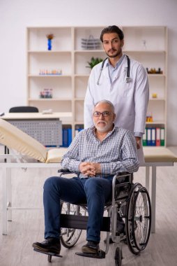 Tekerlekli sandalyedeki yaşlı adam genç erkek doktoru ziyaret ediyor.