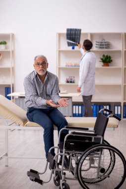 Yaşlı adam genç erkek doktor radyolojisti ziyaret ediyor.