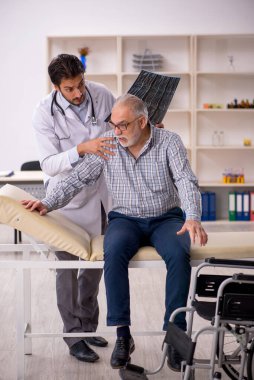 Yaşlı adam genç erkek doktor radyolojisti ziyaret ediyor.
