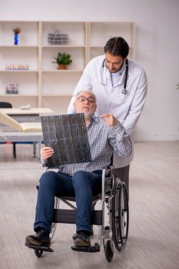 Yaşlı adam genç erkek doktor radyolojisti ziyaret ediyor.