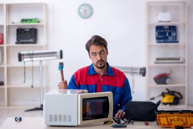 Atölyede fırını tamir eden genç bir erkek tamirci.