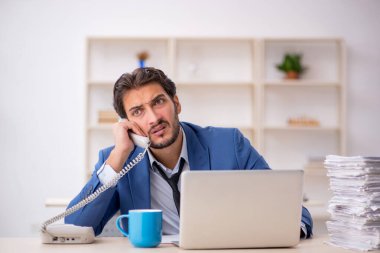 Genç bir erkek çalışan ve ofiste çok fazla iş var.