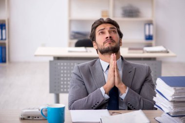 Genç bir erkek çalışan ve ofiste çok fazla iş var.