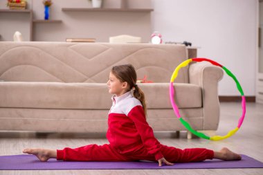 Küçük kız evde spor yapıyor.