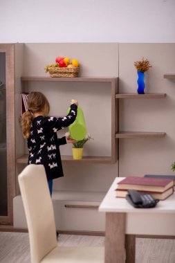Küçük kız evde ev işi yapıyor.