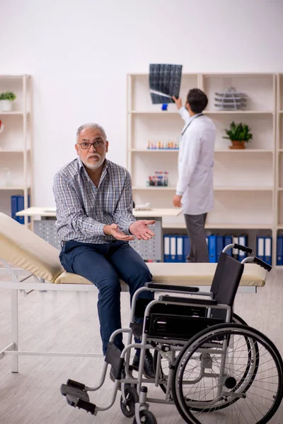 Yaşlı adam genç erkek doktor radyolojisti ziyaret ediyor.