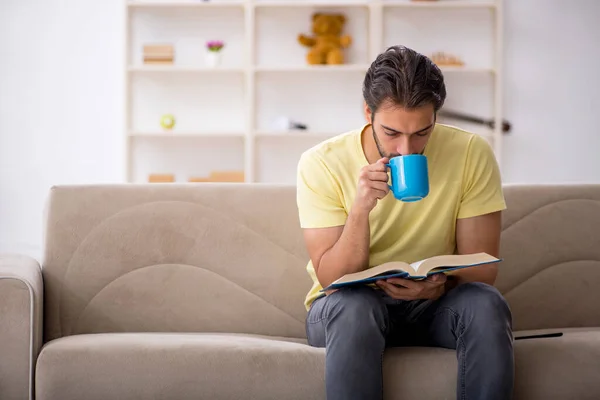 Jeune homme lisant un livre à la maison pendant une pandémie — Photo