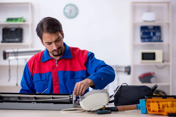 Young male repairman repairing air-conditioner — Stock Photo, Image