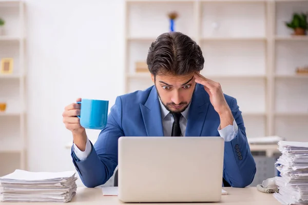 Joven empleado masculino y demasiado trabajo en la oficina —  Fotos de Stock