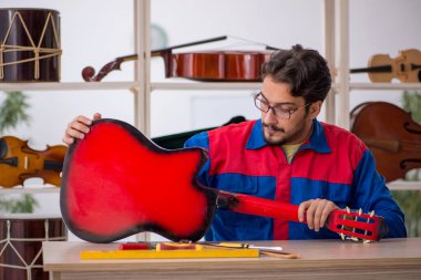 Genç adam atölyede müzik aletlerini tamir ediyor.
