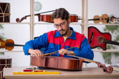 Genç adam atölyede müzik aletlerini tamir ediyor.