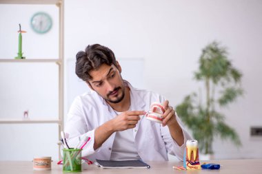 Klinikte çalışan genç erkek dişçi.