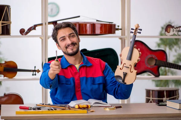 Jongeman repareert muziekinstrumenten in werkplaats — Stockfoto