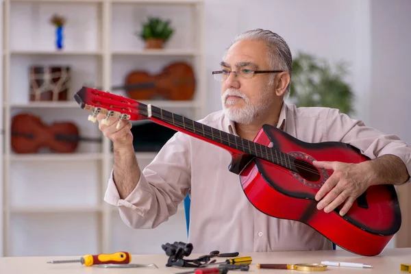 Viejo reparador masculino reparando instrumentos musicales en el taller —  Fotos de Stock
