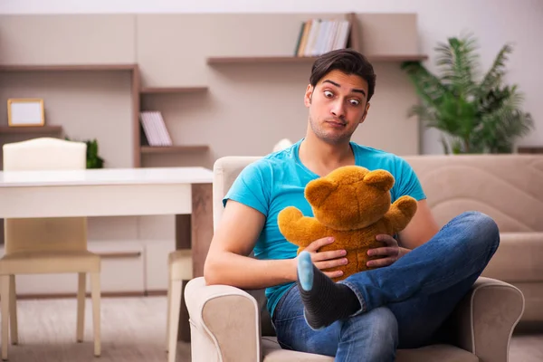 Young man sitting with bear toy at home — Stock Photo, Image
