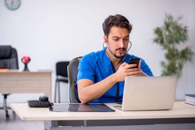 Klinikte çalışan genç erkek doktor.