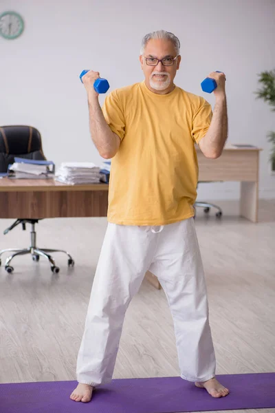 Starý podnikatel zaměstnanec dělá sportovní cvičení v kanceláři — Stock fotografie