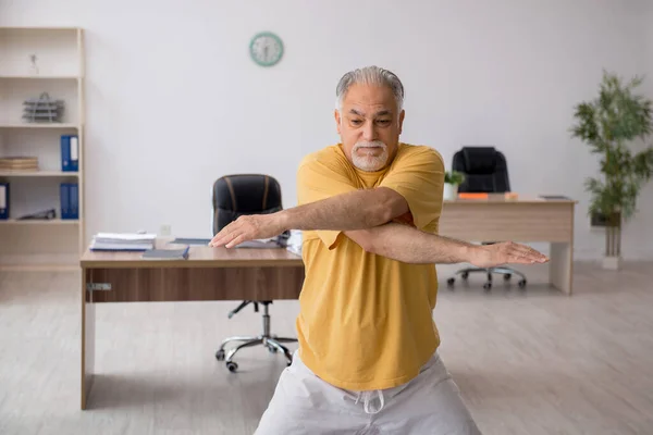 Ein alter Geschäftsmann macht Sport im Büro — Stockfoto