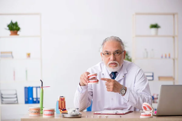 Oude mannelijke tandarts werkzaam in de kliniek — Stockfoto