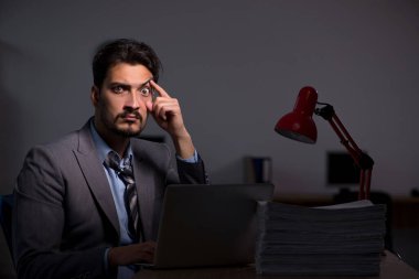 Genç erkek çalışan ofiste geç saatlere kadar çalışıyor.