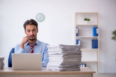 Genç bir erkek çalışan ve ofiste çok fazla iş var.
