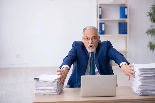 Velho empregado masculino e muito trabalho no escritório — Fotografia de Stock