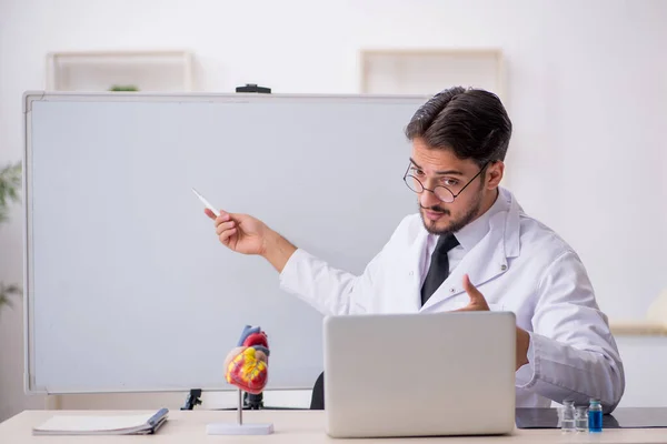 Jonge mannelijke arts cardioloog zit in de klas — Stockfoto