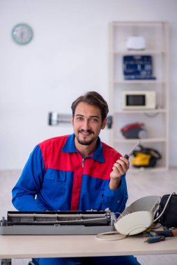 Klimayı tamir eden genç bir erkek tamirci