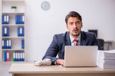 Genç erkek çalışan işyerinde oturuyor.