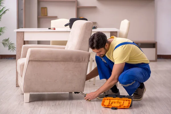 Genç erkek marangoz evde koltuk tamir ediyor. — Stok fotoğraf