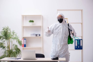 Young male contractor disinfecting office during pandemic