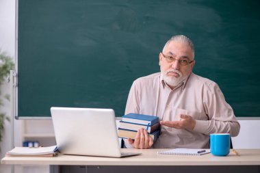 Tahtanın önünde yaşlı bir erkek öğretmen.