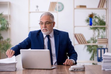 Ofiste çalışan yaşlı bir erkek.