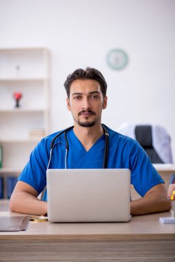 Klinikte çalışan genç erkek doktor.