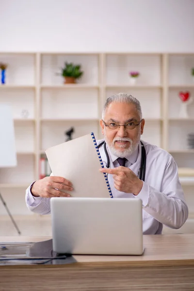 Oude mannelijke arts werkzaam in de kliniek — Stockfoto