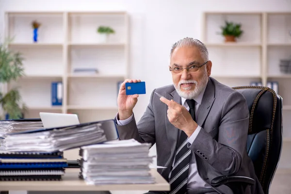 Starý muž zaměstnanec držící kreditní kartu v kanceláři — Stock fotografie