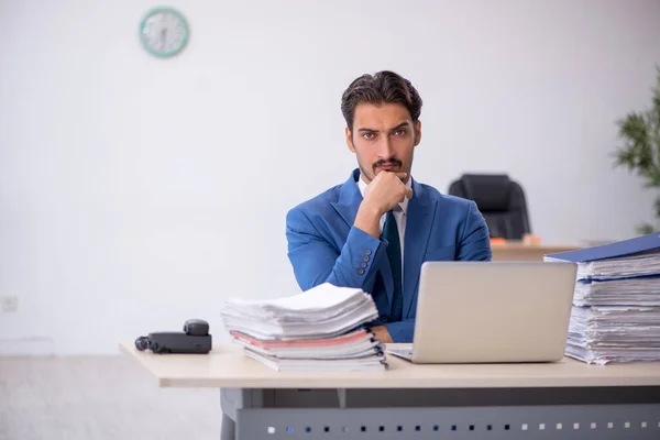 Jovem funcionário masculino e muito trabalho no escritório — Fotografia de Stock