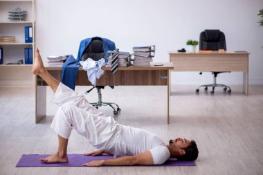 Genç erkek çalışan ofiste spor egzersizleri yapıyor.