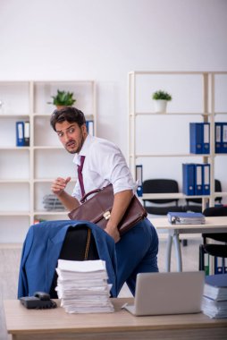 Genç bir erkek çalışan ve ofiste çok fazla iş var.