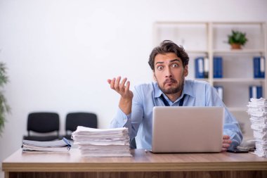 Genç bir erkek çalışan ve ofiste çok fazla iş var.