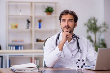 Klinikte çalışan genç erkek doktor.